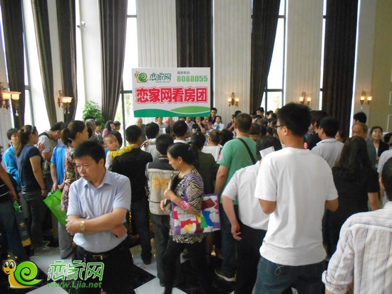購房者圍在沙盤前聽置業(yè)顧問講解沙盤